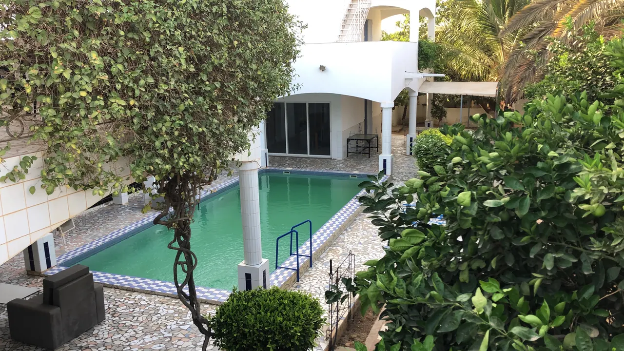 Piscine entourée de jardin et de fauteuils